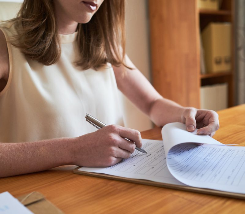 Woman signing paper on clipboard
